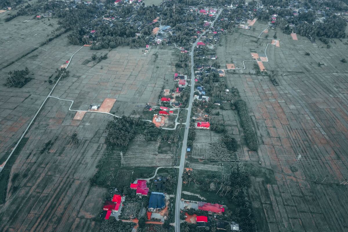 Vista aérea de uma povoação dispersa entre campos agrícolas e uma estrada central